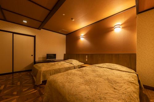 a room with two beds and a laptop on a desk at Kinugawa Hotel Mikazuki in Nikko