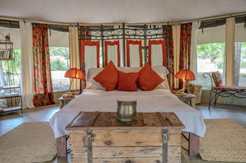 a bedroom with a large bed with red pillows at Dolly Farm & River Camp, Luxury Tents in Usa River