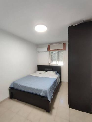a bedroom with a bed with a blue comforter at Home with a balcony by the sea 60-5 in Qiryat H̱ayyim