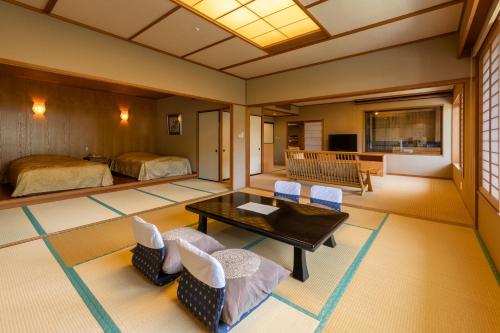 a room with two beds and a table and chairs at Kinugawa Hotel Mikazuki in Nikko