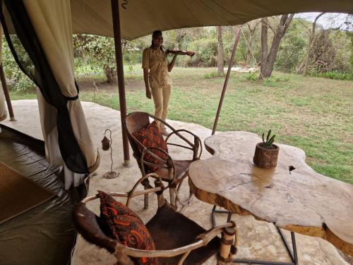 a man standing under a tent with a table and chairs at Dolly Farm & River Camp, Luxury Tents in Usa River