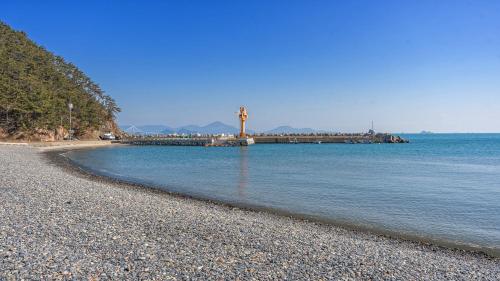 una spiaggia rocciosa con un molo in acqua di Geoje Highend Spa Pool Villa Duplex, Indoor BBQ a Geoje