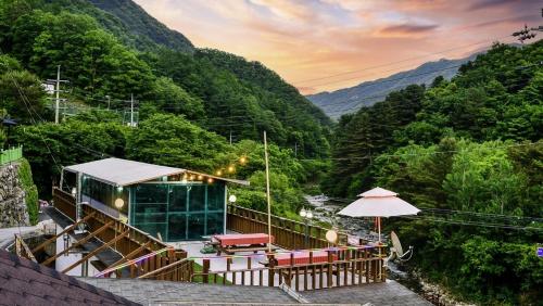 a building with chairs and an umbrella on a mountain at Gapyeong Sangol Spa Pension in Gapyeong