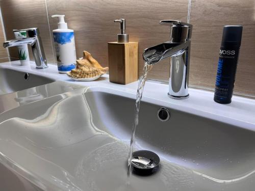 a bathroom sink with water running from a faucet at vakantiewoning met jacuzzi Forêt d'Animaux in Frahan