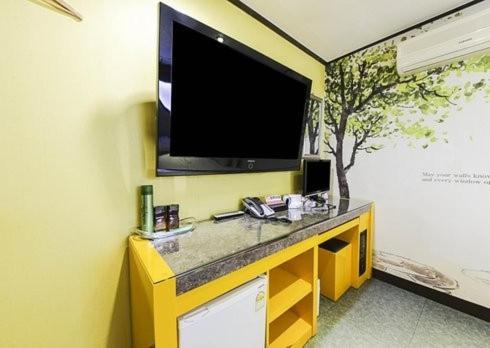 a television on a wall with a yellow wall at Hotel I Chuncheon Branch in Chuncheon