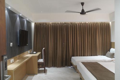 a hotel room with two beds and a television at Hotel Vrindavan Palace in Indore