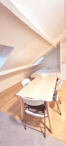 Cette chambre mansardée comprend une table et des chaises. dans l'établissement Appartement pré de Paris, à Gagny