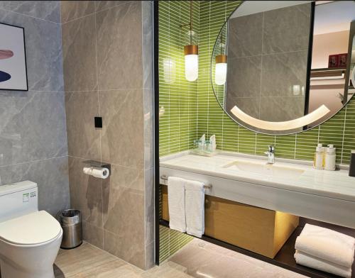 a bathroom with a toilet and a sink and a mirror at Holiday Inn Foshan Nanhai Central by IHG in Foshan