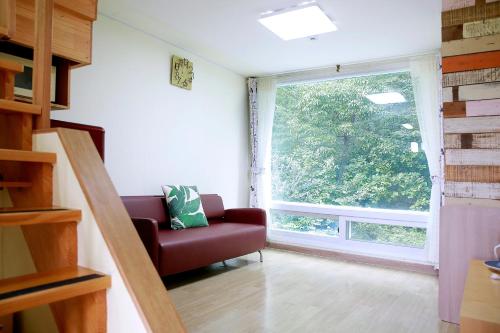 a living room with a red couch and a large window at Paju Maribyeol Pension in Saech'aei