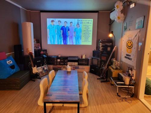 a living room with a table and a projection screen at Donghae Mookhoae Pension in Mukho-dong