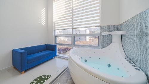 a bathroom with a tub and a blue couch at Gapyeong Rapunzel Kids Poolvilla in Gapyeong