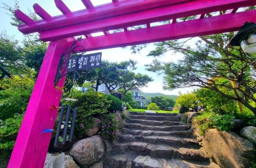 a pink archway with stairs leading to a house at Samcheok Rose Valley Pension in Samcheok