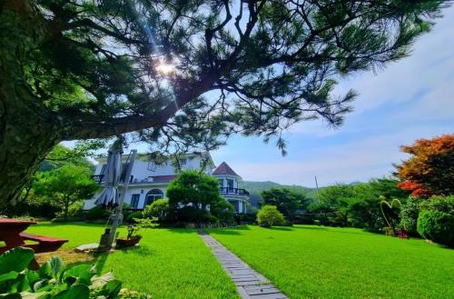 a large white house with a green lawn at Samcheok Rose Valley Pension in Samcheok