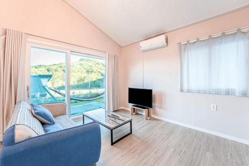 a living room with a couch and a tv at Gangneung Dawon Forest Private Pension in Gangneung