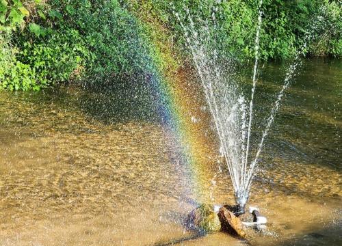 a fountain with a rainbow in the water at Pocheon Lodge Caravan Camping Site in Pocheon