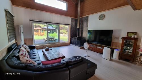 a living room with a black leather couch and a tv at Bauhaus In Wonju in Wonju