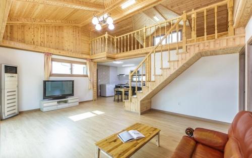a living room with a wooden staircase and a television at Hongcheon Oz Pension in Hongcheon