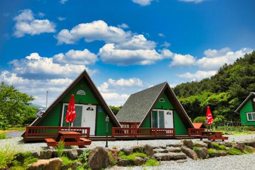 a green house with two red flags in front of it at Pinescent Pension in Cheorwon