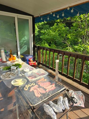 a grill with meat on a table on a deck at Pyeongchang Heungjeong Valley 409 Pension in Pyeongchang 
