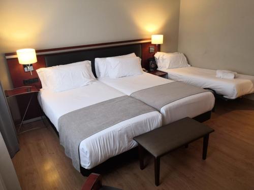two beds in a hotel room with two lamps at Abba Euskalduna Hotel in Bilbao