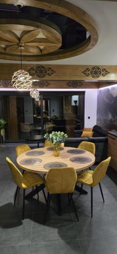 a dining room with a table and yellow chairs at Porębiańska Osada Resort & Spa in Szlembark