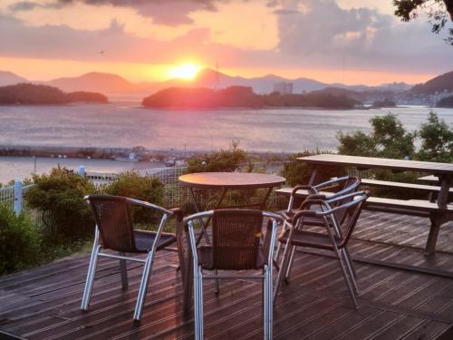 un tavolo e sedie su una terrazza con il tramonto di Yeosu Gyeongdo Pension a Yeosu