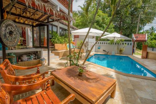 a patio with a wooden table and chairs next to a pool at Penthouse Crystal Bay Apartments in Ban Lamai