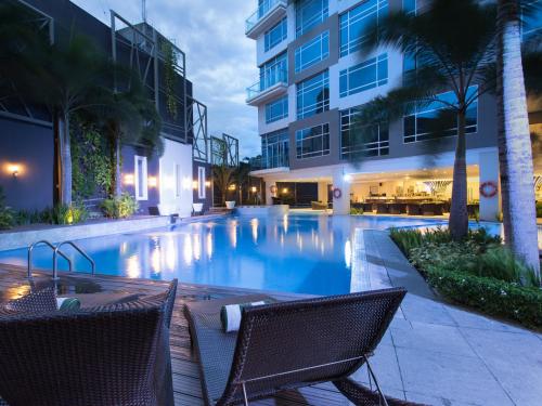 a swimming pool with two chairs in front of a building at Greenleaf Hotel Gensan in General Santos