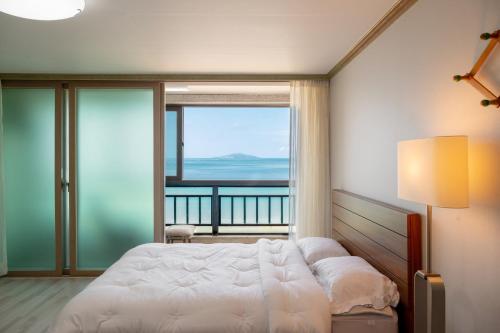 a bedroom with a bed and a view of the ocean at Wando Love You Pension in Wando