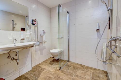 a bathroom with a shower and a toilet and a sink at Berghotel Jaga-Alm in Zell am See
