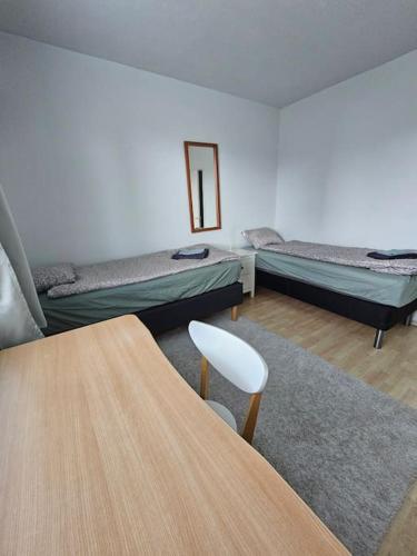 a room with two beds and a table and a chair at Satakieli - 2 bedroom apartment incl free parking and wifi max 5 person in Harjavalta