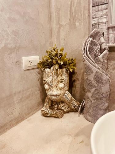 a statue of a baby groot sitting next to a lightswitch at Destination39 in Thalang