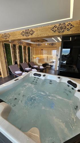 a jacuzzi tub in a room with chairs at Porębiańska Osada Resort & Spa in Szlembark