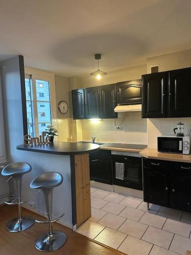une cuisine avec des armoires noires et un comptoir dans l'établissement Appartement Traversant avec vue exceptionnelle, à Saint-Étienne