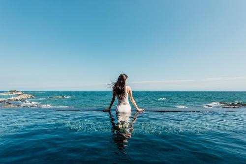 a woman standing in the water in the ocean at Pohang Case Poolvilla in Hajŏng-ni