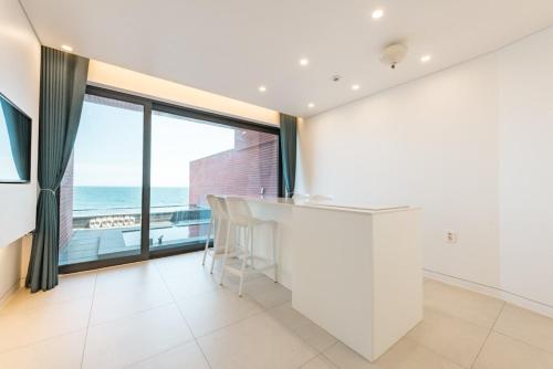 a white kitchen with a counter and a large window at Pohang Case Poolvilla in Hajŏng-ni