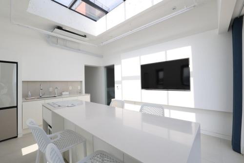 a white kitchen with a large white table and chairs at Pohang Case Poolvilla in Hajŏng-ni