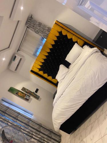 a bed with a yellow headboard in a room at RichJ Luxury Apartments in Ebowe