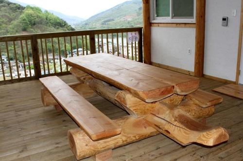 a wooden bench sitting on a deck with a table at Gurye Tongnamu Pension in Gurye