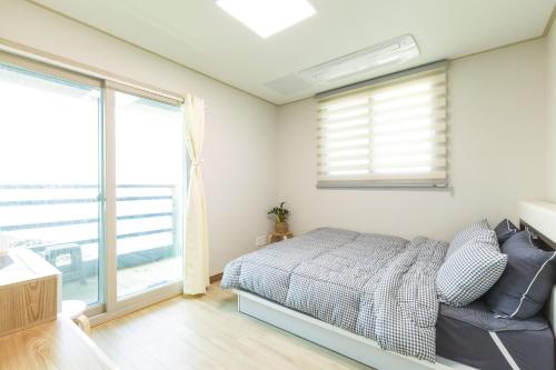 a bedroom with a bed and a window at Jeju ongpo490 Pension in Jeju