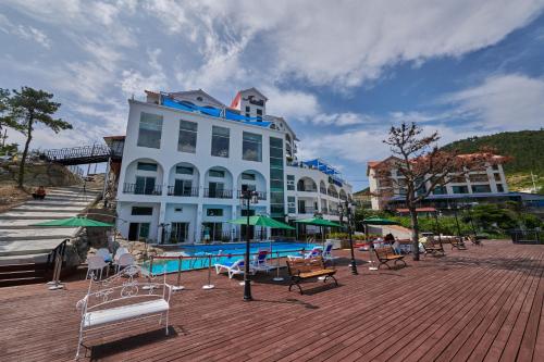 a large white building with a swimming pool and benches at Ilmare Byeonsan Resort in Buan