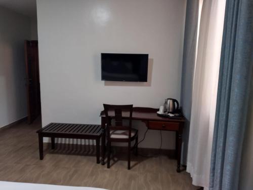 a room with a desk and a table and a television at Twiga Whitehouse Villa in Nakuru