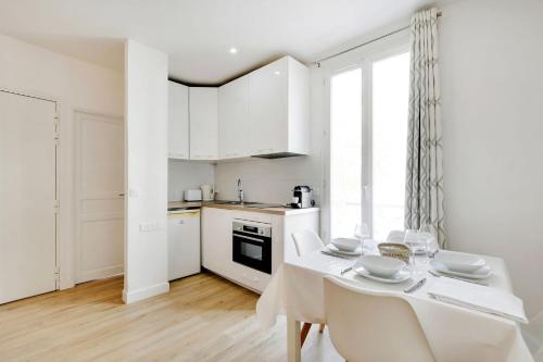 une cuisine et une salle à manger avec une table et des chaises blanches dans l'établissement Newly restored appartment - Montmartre, à Paris