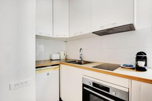 une cuisine avec des armoires blanches et un évier dans l'établissement Newly restored appartment - Montmartre, à Paris
