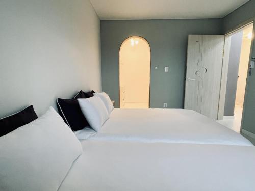 a bedroom with a large white bed and an open door at Jeju Private Poolvilla Gwakjidaon Stay in Namŭm-ni