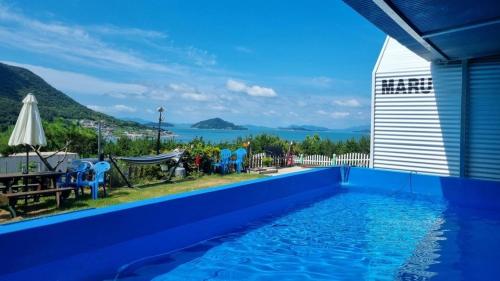a blue swimming pool with a view of the ocean at Yeosu Maru Pension in Wŏnp'o