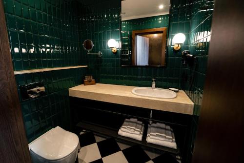 a green tiled bathroom with a sink and a toilet at Hotel Erdeli by Derenivska Kupil in Nyzhne Solotvyno