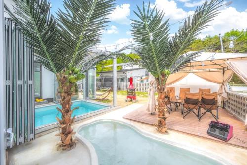 a swimming pool with palm trees next to a house at gyeongju memoareu kieokjangchi in Gyeongju