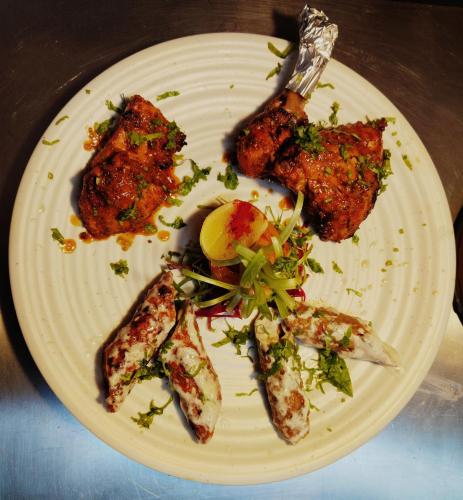 a white plate of food with fish on it at Hotel Sakura by Maps in Gurgaon