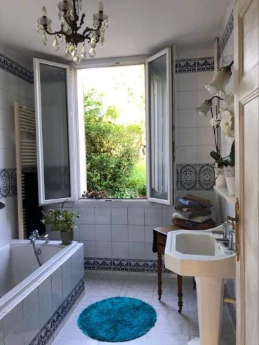 une salle de bain avec une baignoire, un lavabo et une fenêtre dans l'établissement Bourgogne grande maison avec jardin à la française, à Pontailler-sur-Saône